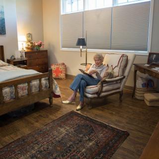 A person reading a book in a cozy bedroom setting.