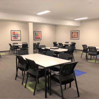 An empty classroom or meeting space with tables and chairs arranged neatly.