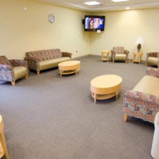 A comfortable waiting room with sofas and a television on the wall.
