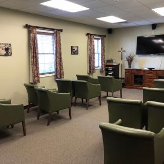A cozy meeting room with green chairs and a television.