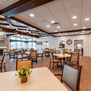A spacious and modern dining room with neatly arranged tables and chairs, featuring elegant lighting and decor.