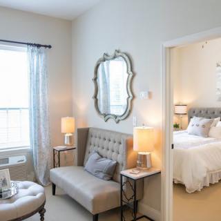 A cozy and elegantly decorated bedroom with a comfortable seating area, featuring soft lighting and stylish furnishings.