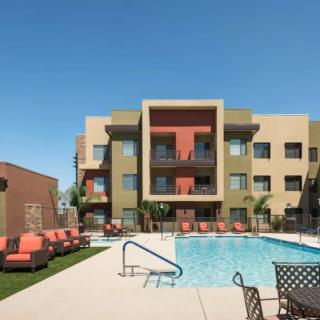 Modern apartment complex with a swimming pool and lounge chairs.