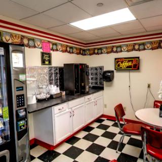 A cozy break room featuring a vending machine, coffee maker, and checkered flooring.