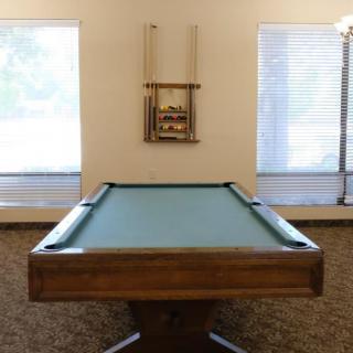 A billiards table in a game room with cue sticks mounted on the wall.