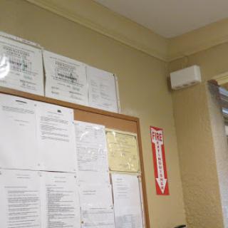 An office wall displaying certificates and various documents on a bulletin board.
