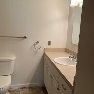 A simple bathroom with a sink, vanity, and toilet.