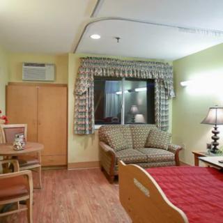 A well-furnished hospital room with a bed, sofa, and table.