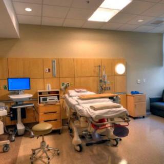A well-equipped maternity room with medical equipment and a hospital bed.