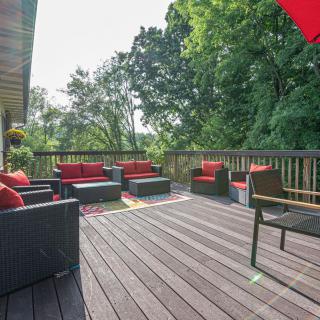 A spacious outdoor deck with comfortable seating and red cushioned furniture, surrounded by greenery.