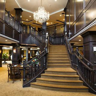 A luxurious hotel lobby featuring a grand staircase and an ornate chandelier.