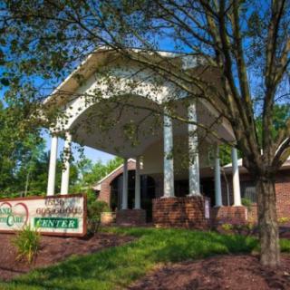 A building entrance with a sign and surrounding greenery.