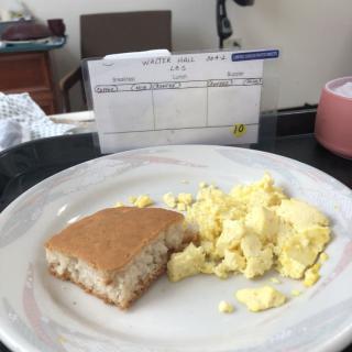 A breakfast meal consisting of scrambled eggs and a pancake on a plate.