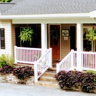 A charming house with a welcoming front porch adorned with hanging plants.