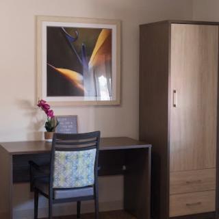 A simple and organized office space featuring a desk, chair, storage cabinet, and artwork.