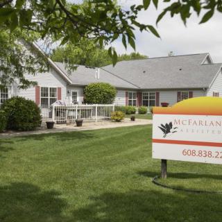 A residential building with a well-maintained lawn and a sign in the foreground.