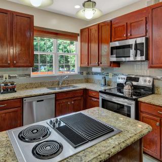 A modern kitchen with stainless steel appliances and wood cabinetry, featuring granite countertops.