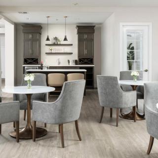 A modern and elegant cafe interior with grey chairs, round tables, and a stylish bar area.