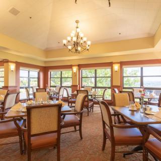 A well-lit dining area with elegant furniture and a central chandelier.
