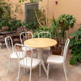 A cozy patio area featuring a round table with four white chairs surrounded by lush green plants.