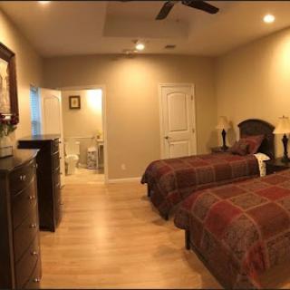 A cozy bedroom featuring twin beds with plaid bedding, complemented by warm lighting and a bathroom entrance.