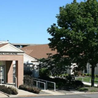 A view of a building entrance with surrounding greenery and a clear sky.