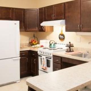 A modern kitchen with dark wood cabinets and white appliances.