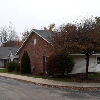 A suburban residential building with brick exterior and a tree-lined sidewalk.