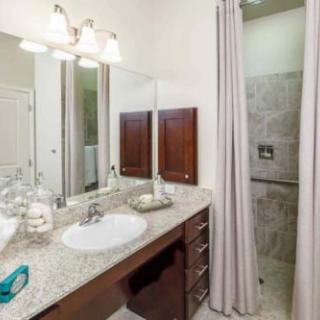 A modern bathroom featuring a sink, mirror, and shower area with a curtain.