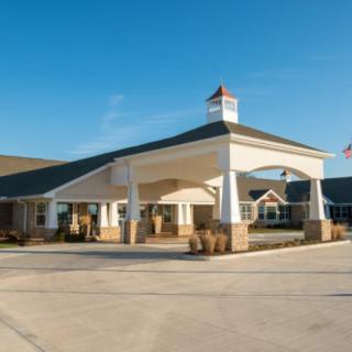 A large building with a covered entrance and driveway on a clear day.