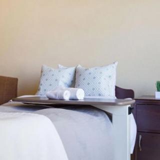 A cozy and minimalist bedroom setup with neatly arranged pillows and a bedside table.