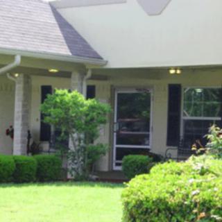 A small porch with a garden and well-maintained lawn.