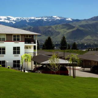 A scenic view of a building set against snow-capped mountains and lush green surroundings.