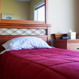 A cozy bedroom setup with a red blanket and wooden furniture.