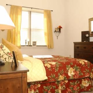 A cozy bedroom with a floral bedspread and warm lighting.