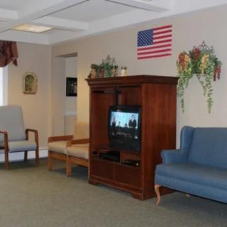 A waiting room with a television, chairs, and an American flag on the wall.