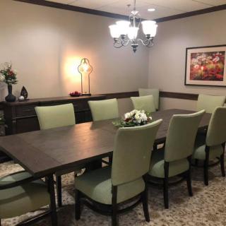 A well-appointed dining room with a long table and chairs, featuring a chandelier and decorative elements.