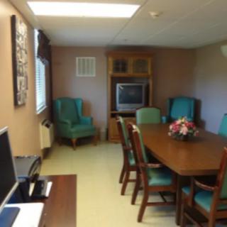 A small conference room featuring a table with chairs, a television, and a computer.
