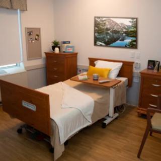 A well-appointed hospital room featuring a single bed with wooden furniture and calming decor.