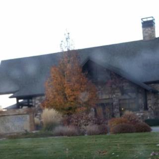 A charming stone house with a sloped roof and autumn foliage in the garden.