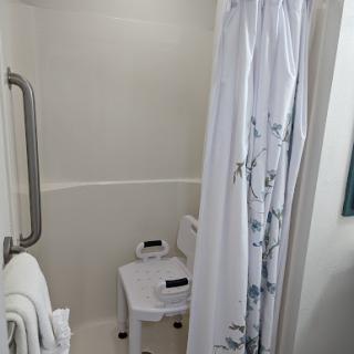 A tidy and accessible bathroom with a shower and neatly arranged towels.
