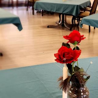 A beautifully set table with red roses in a vase, ready for guests in a restaurant.