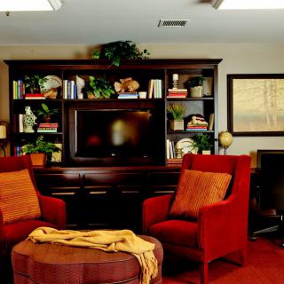 A cozy living room with red armchairs and a bookshelf surrounding a television.