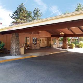 The entrance of a hotel with a covered driveway and rustic architectural design.
