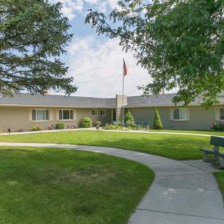 A single-story building with a well-maintained lawn and a flagpole in front.