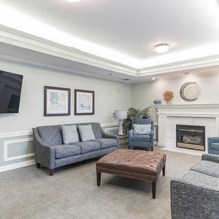 A well-furnished living room featuring a comfortable sofa set, a central coffee table, and a fireplace with elegant wall art.