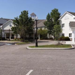 A residential building with a parking lot and trees during the daytime.