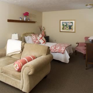 A cozy bedroom interior featuring an armchair, bed, and decorative elements.