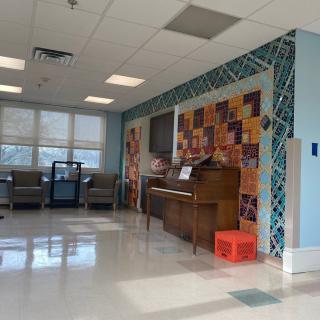 A spacious waiting room featuring a piano and colorful mural on the wall.