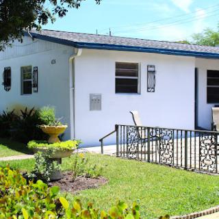A charming white house with a well-maintained garden and decorative fencing.
